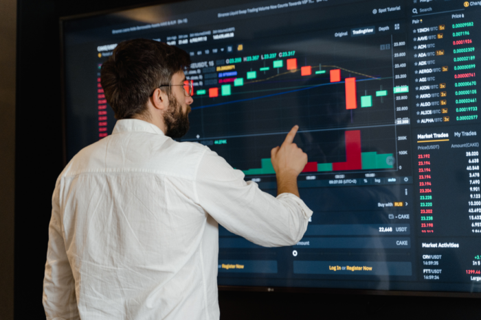 A professional pointing at a digital chart on a large screen, demonstrating the practical applications of management education in financial analysis and market trends.